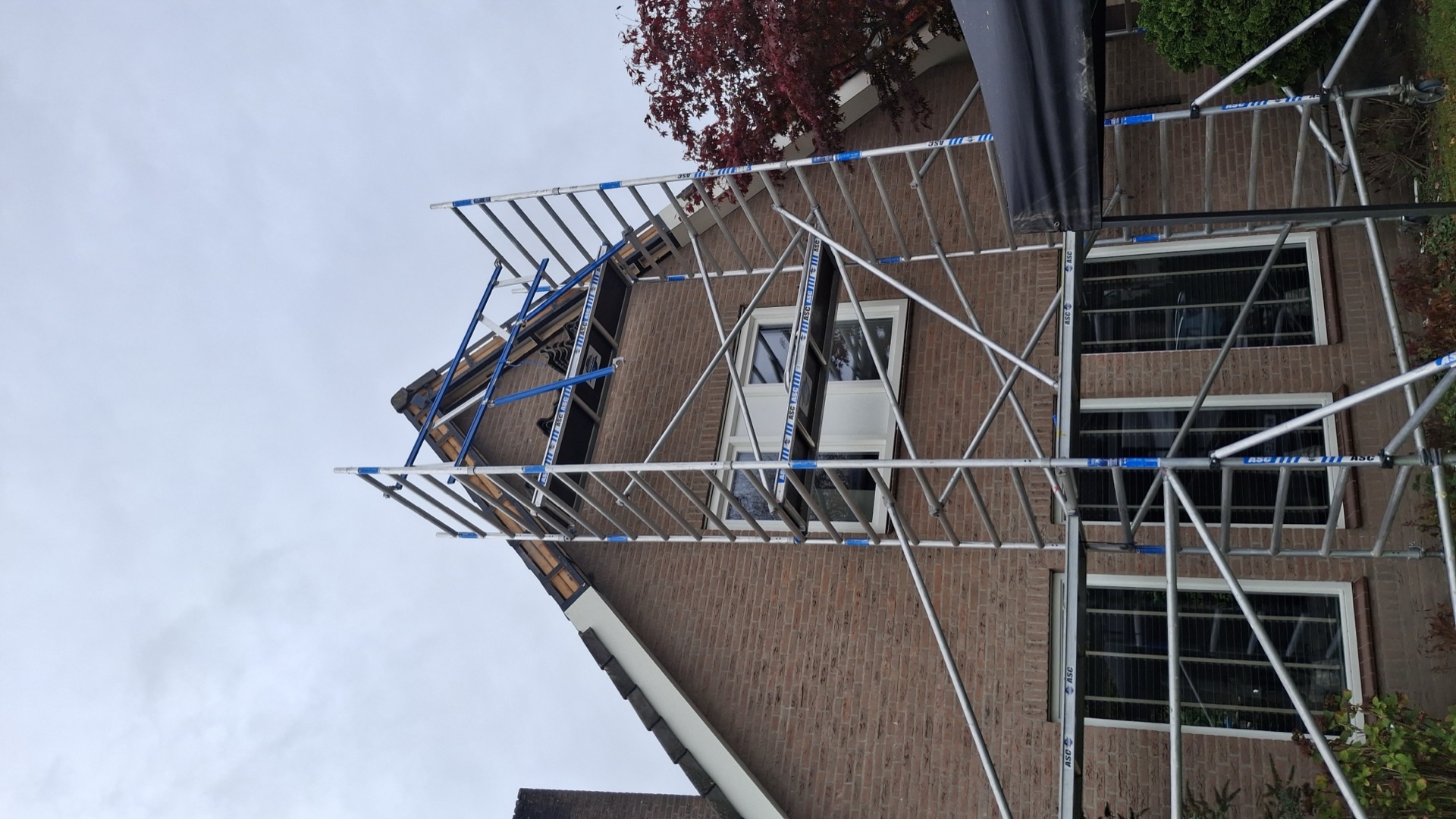 Steiger opgebouwd tegen de gevel voor werkzaamheden bij de nok van het dak