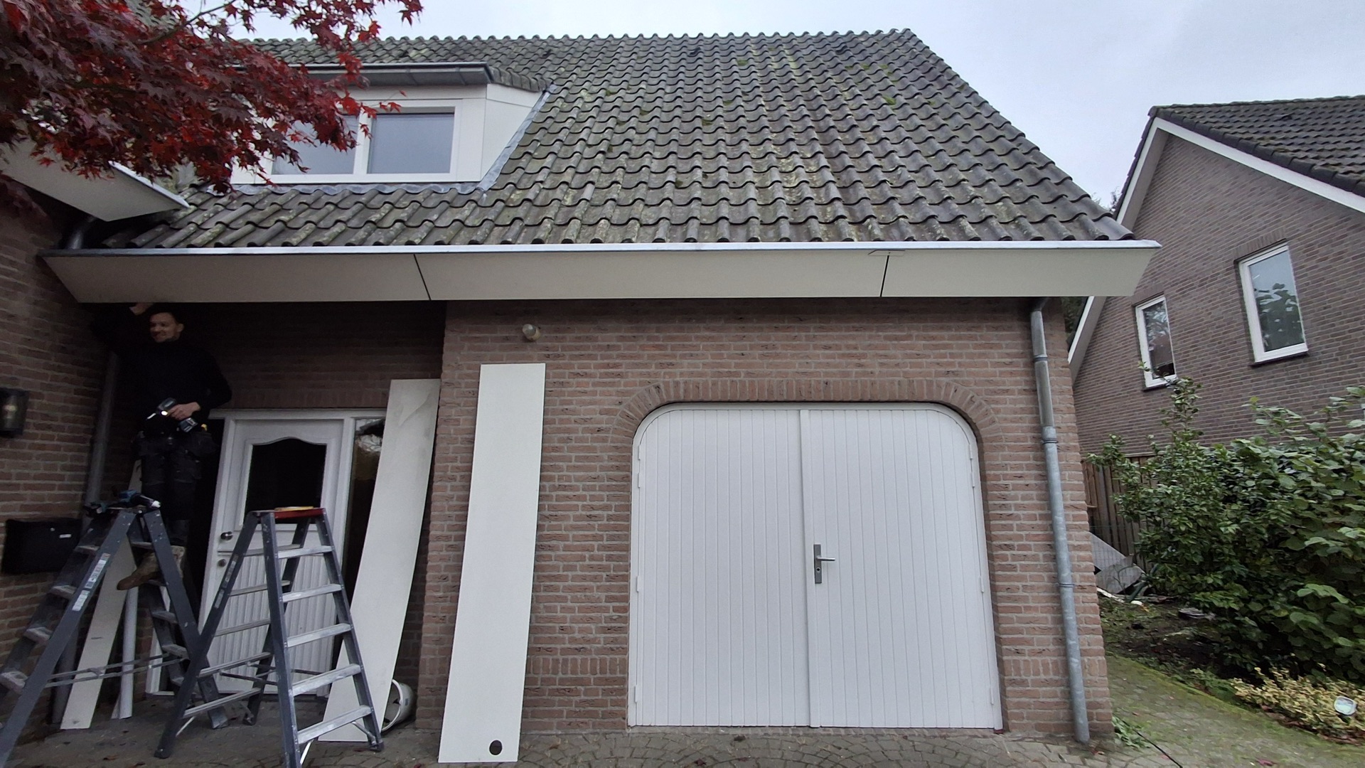Medewerker monteert nieuwe boeiboorden onder de dakrand van een garage
