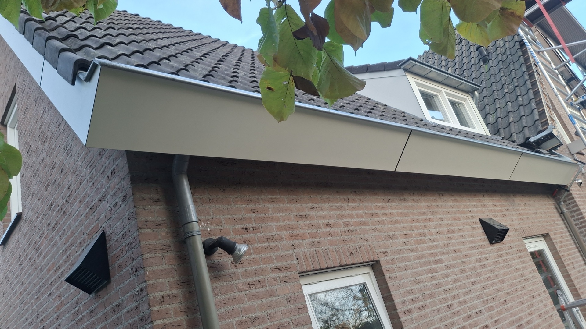 Nieuw afgewerkte aluminium daktrim en dakgoot langs de gevel