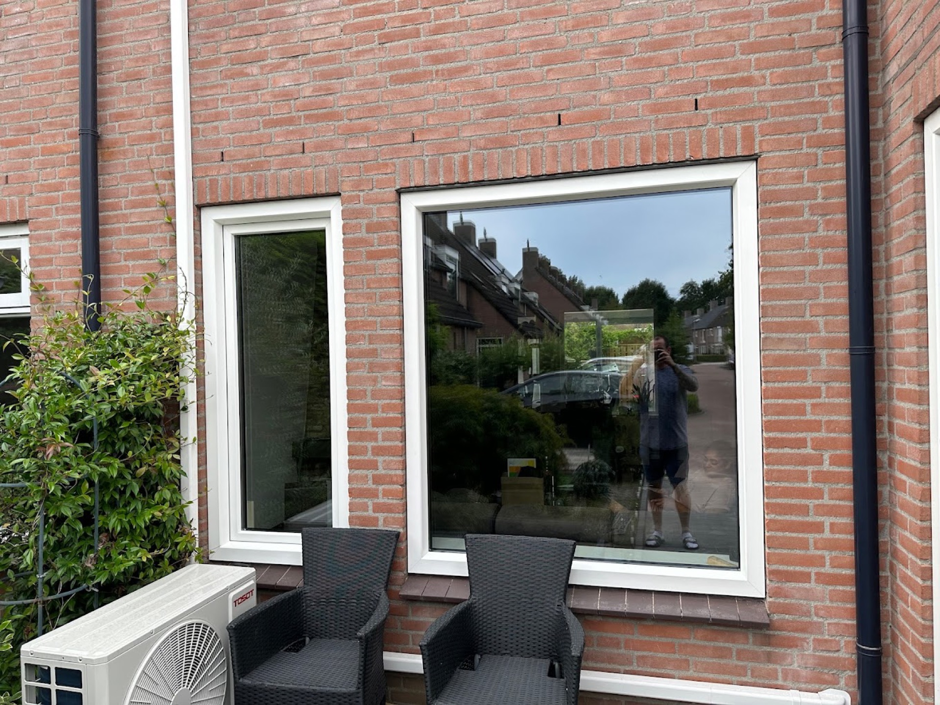 Twee witte kunststof kozijnen in een bakstenen gevel, met loungestoelen op het terras ervoor