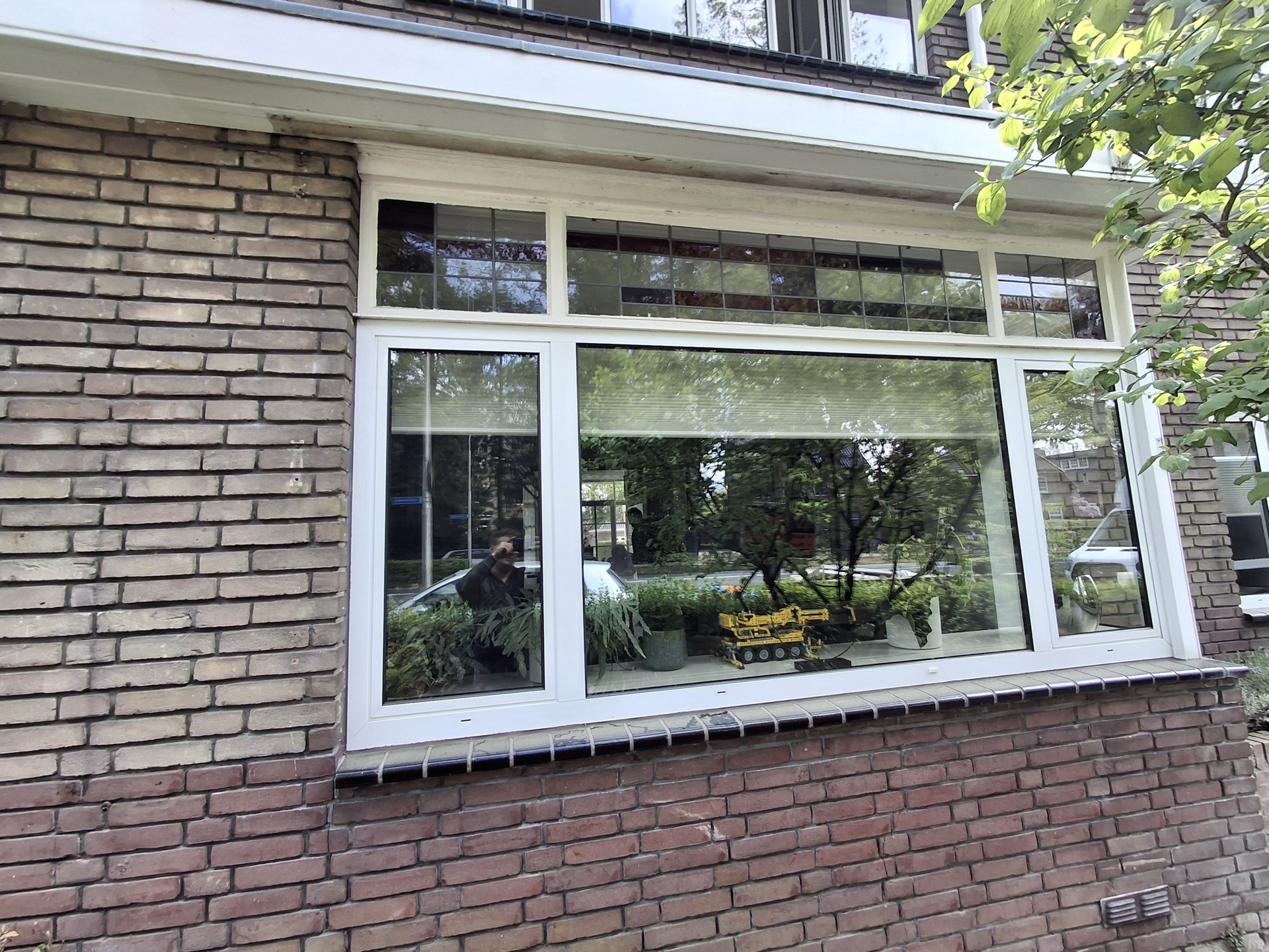 Nieuw wit kunststof kozijn onder de behouden glas-in-lood bovenlichten van een oudere woning