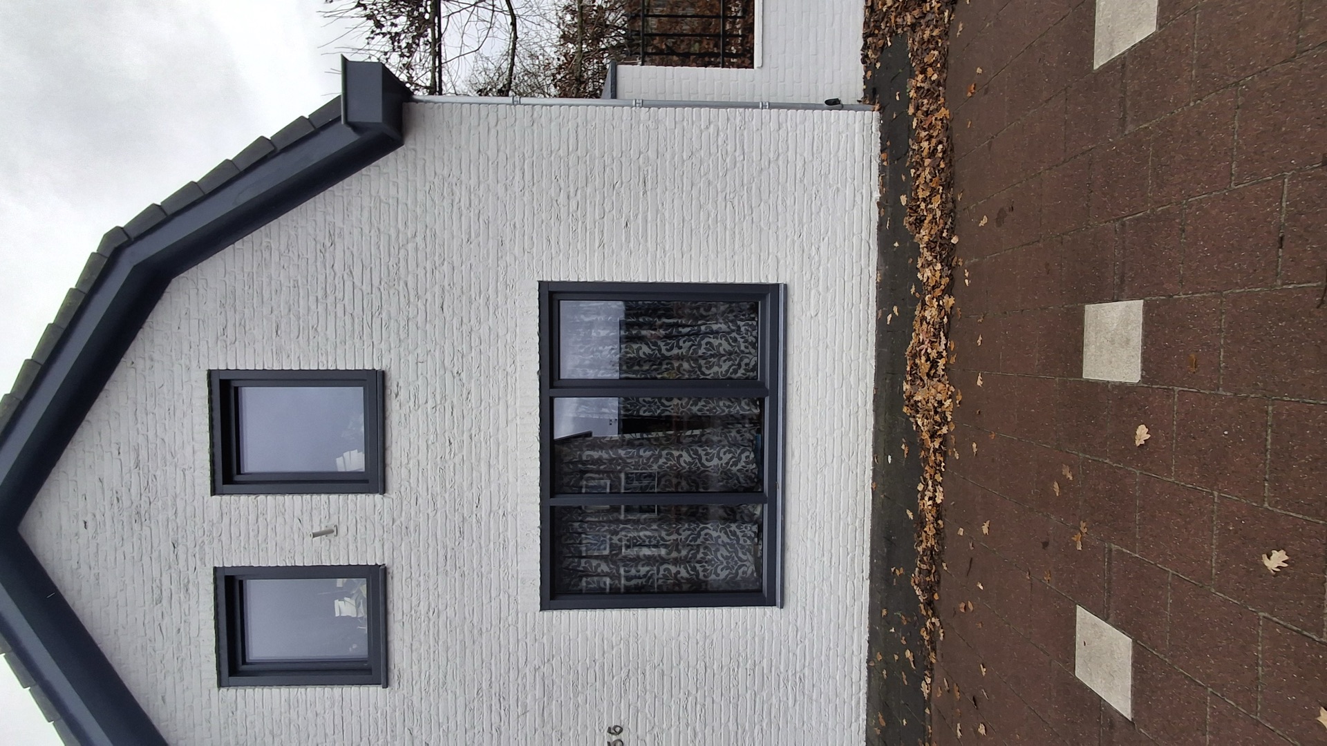 Slanke antracietkleurige kozijnen in een wit gestucte gevel