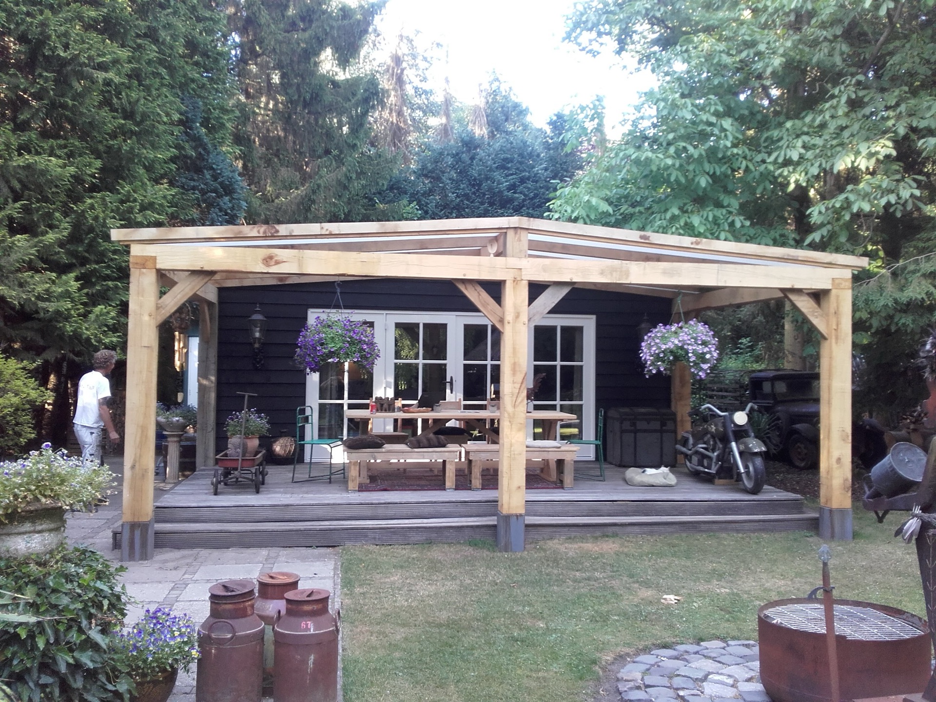 Houten veranda met zithoek en eettafel tegen een zwart geschilderde woning