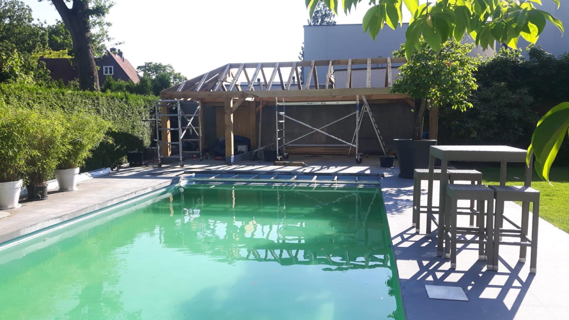 Houten dakconstructie van een bijgebouw met steiger, nog in aanbouw naast een zwembad