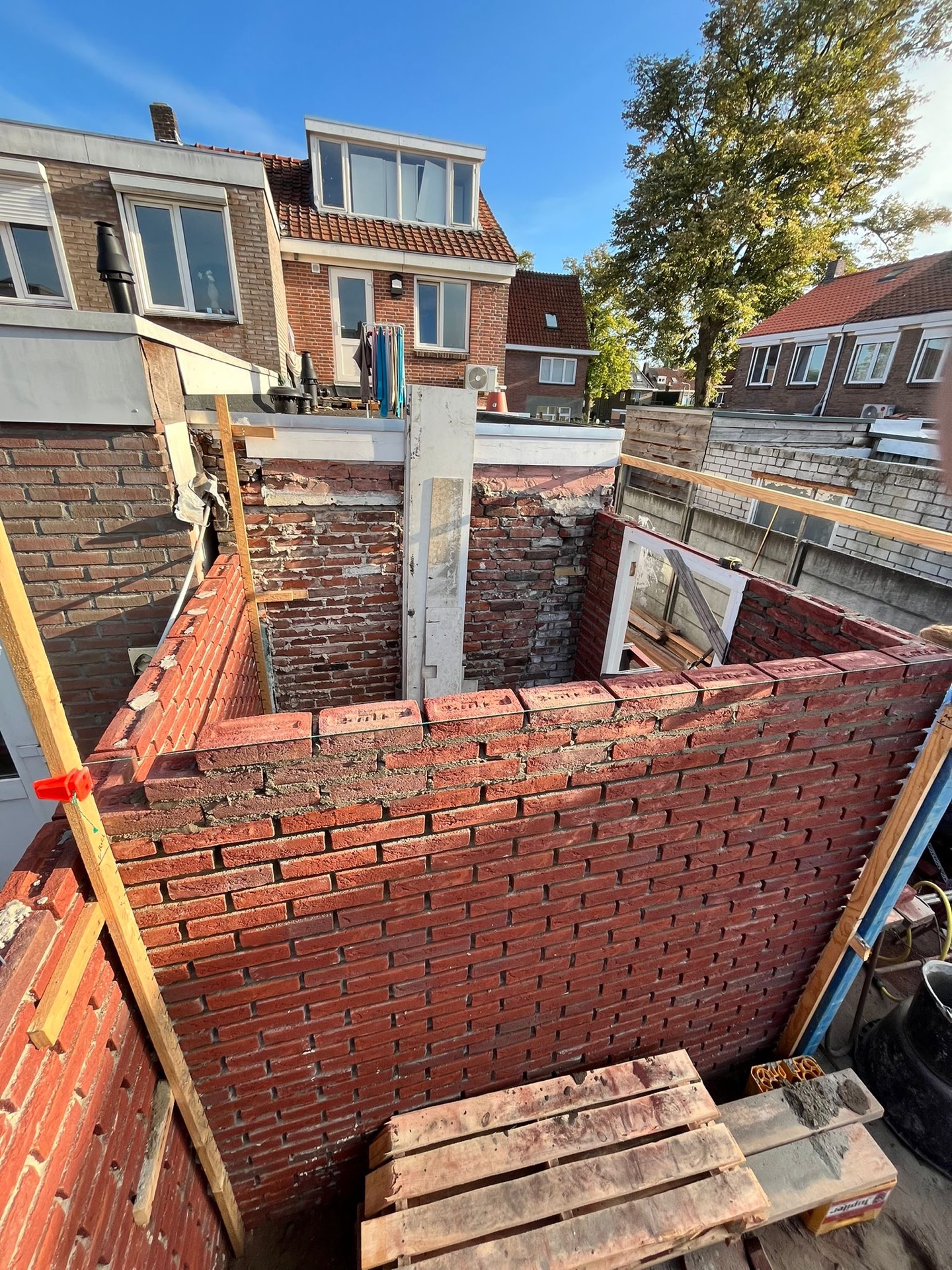 Bakstenen aanbouw in de ruwbouwfase, gezien van bovenaf met de kozijnopening in de muur
